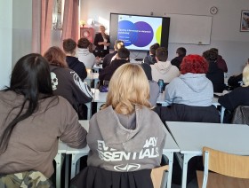 zdjęcie uczniów w klasie, patrzących na tablicę z prezentacją