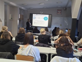 zdjęcie uczniów w klasie, patrzących na tablicę z prezentacją