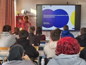 zdjęcie uczniów w klasie, patrzących na tablicę z prezentacją