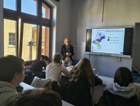 zdjęcie uczniów w klasie, patrzących na tablicę z prezentacją