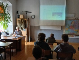 zdjęcie uczniów w klasie, patrzących na tablicę z prezentacją