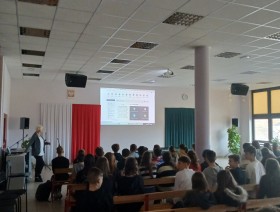 zdjęcie uczniów w klasie, patrzących na tablicę z prezentacją